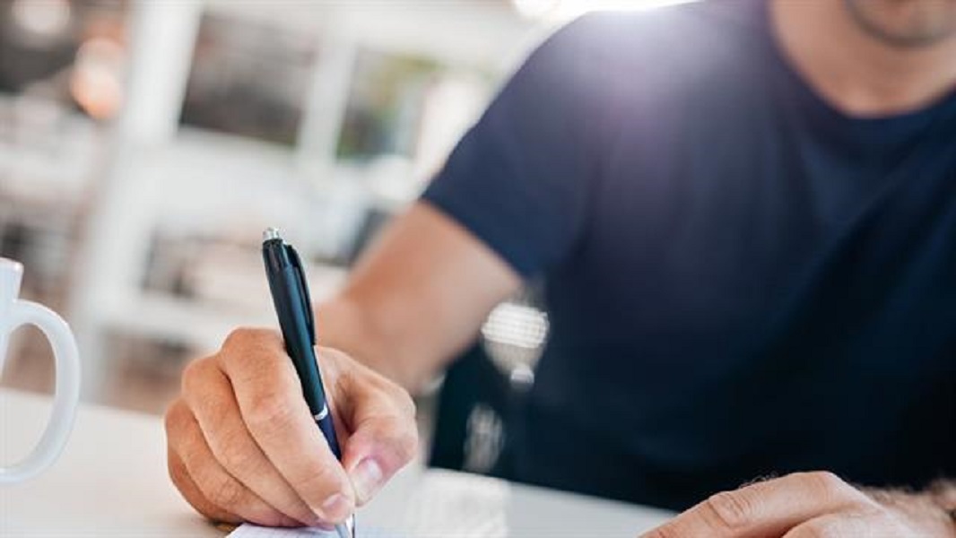 People pen. Man hand holding a Note book. Man writing on the Table working Night. Write to work in an Office.